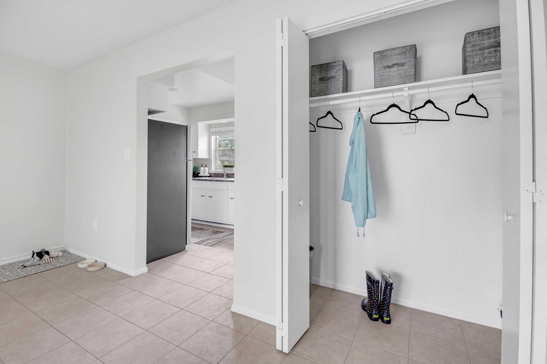 A closet with clothes hanging on the wall and a pair of boots on the floor.