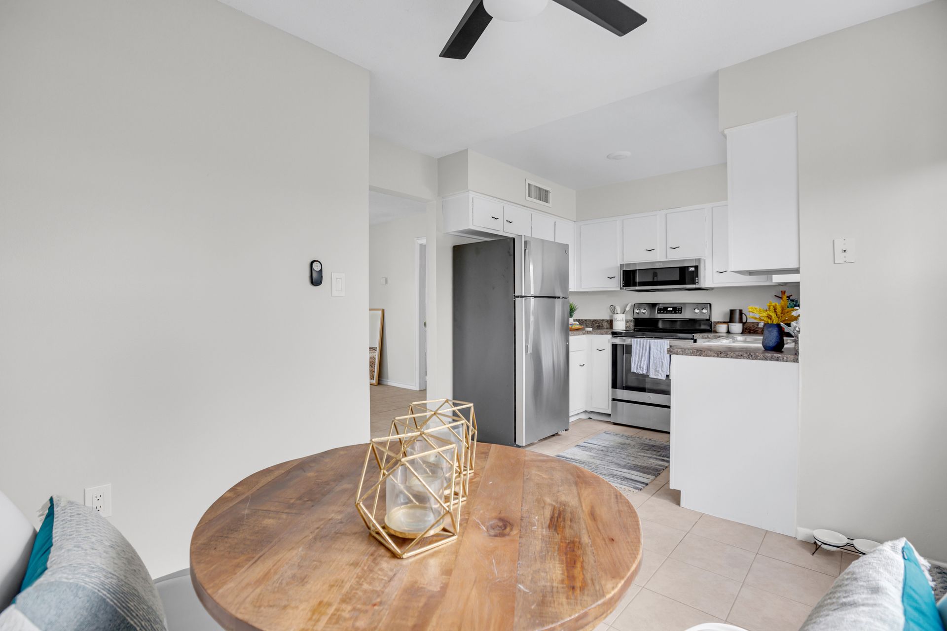 A living room with a round wooden table and a ceiling fan.