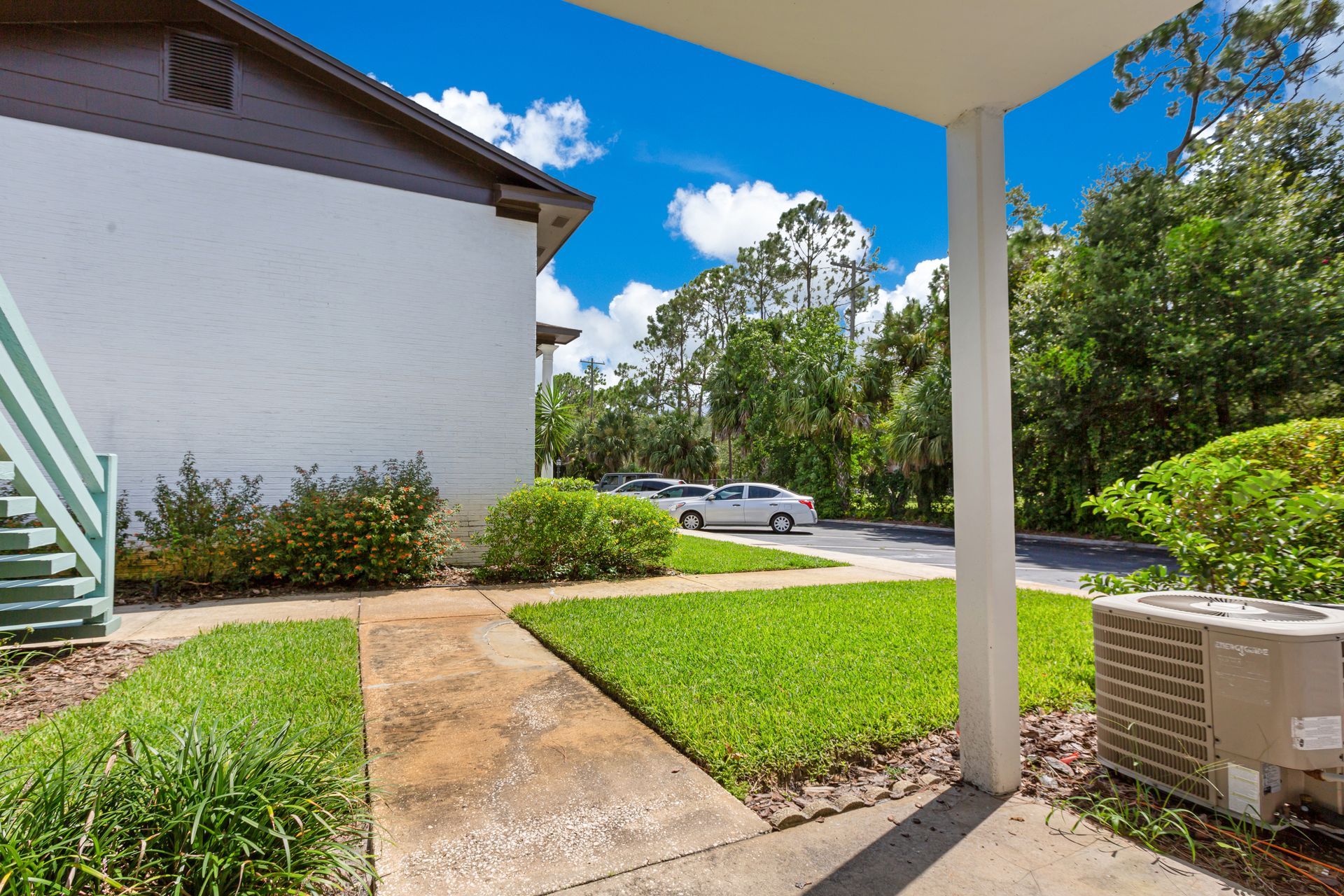 A white car is parked on the side of the road in front of a house.