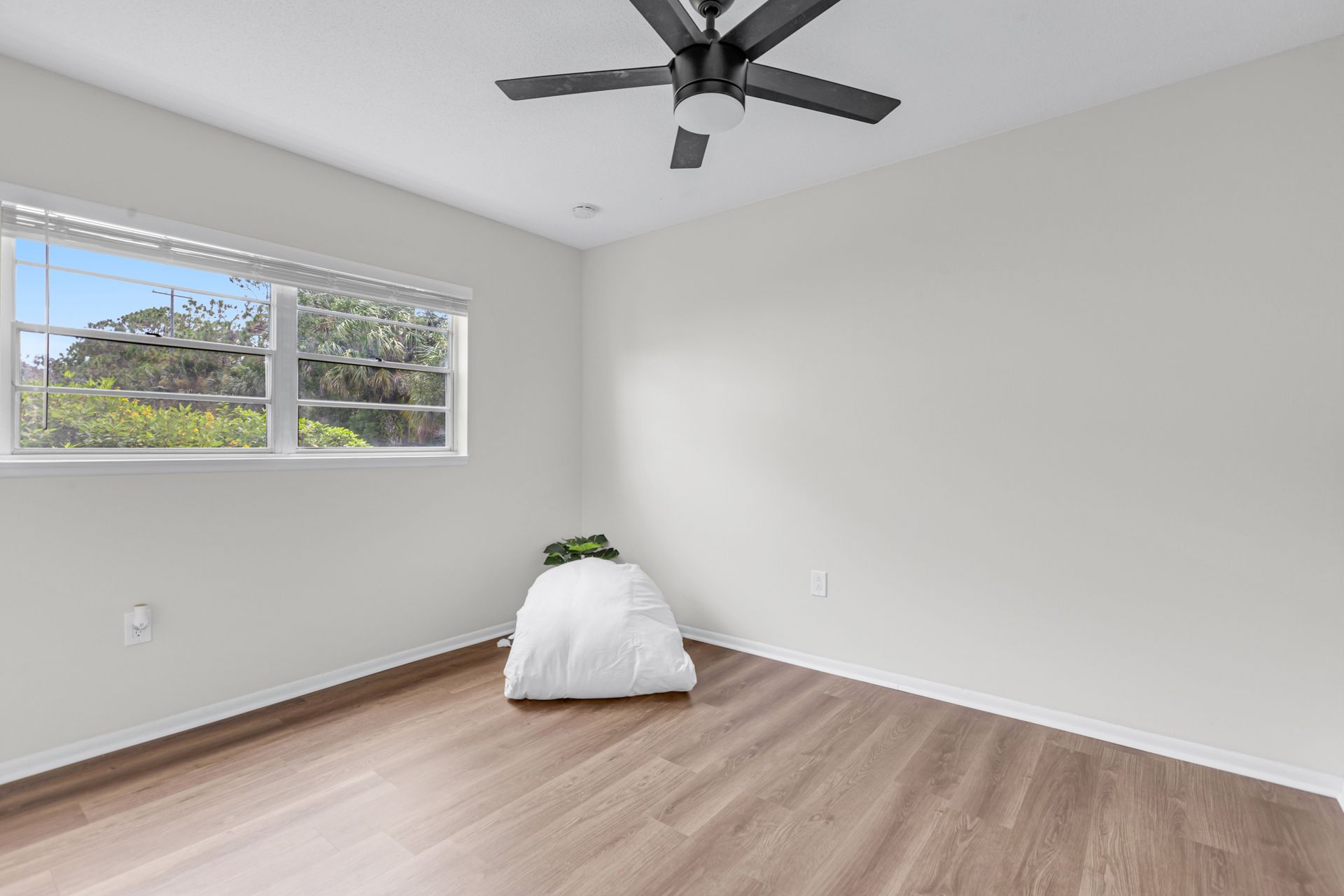 An empty bedroom with a bed and a ceiling fan.