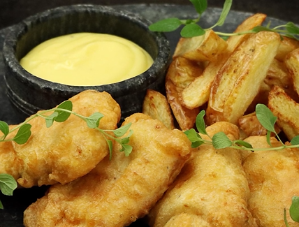 Um prato de peixe frito e batatas fritas com molho.