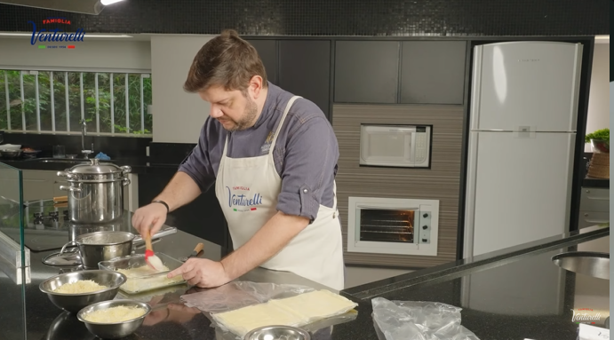 Um homem de avental está preparando comida na cozinha.