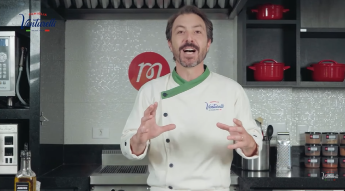 Um homem com uniforme de chef está em pé na cozinha.