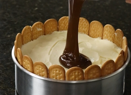 Chocolate está sendo derramado em um bolo com biscoitos