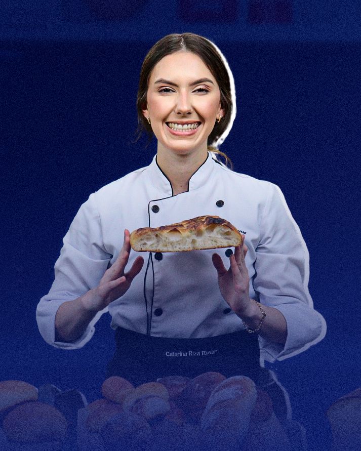 Uma mulher com uniforme de chef está segurando um pedaço de pão.