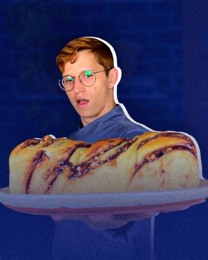 Um homem de óculos está segurando um pedaço de pão de canela
