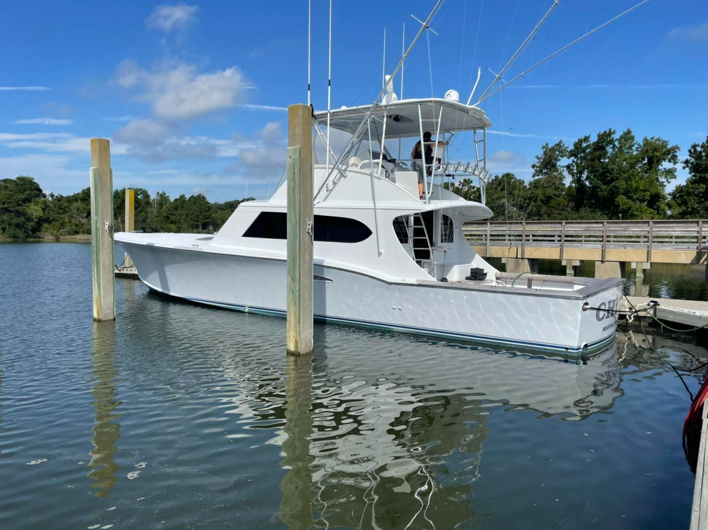 A white boat is docked at a dock in the water.