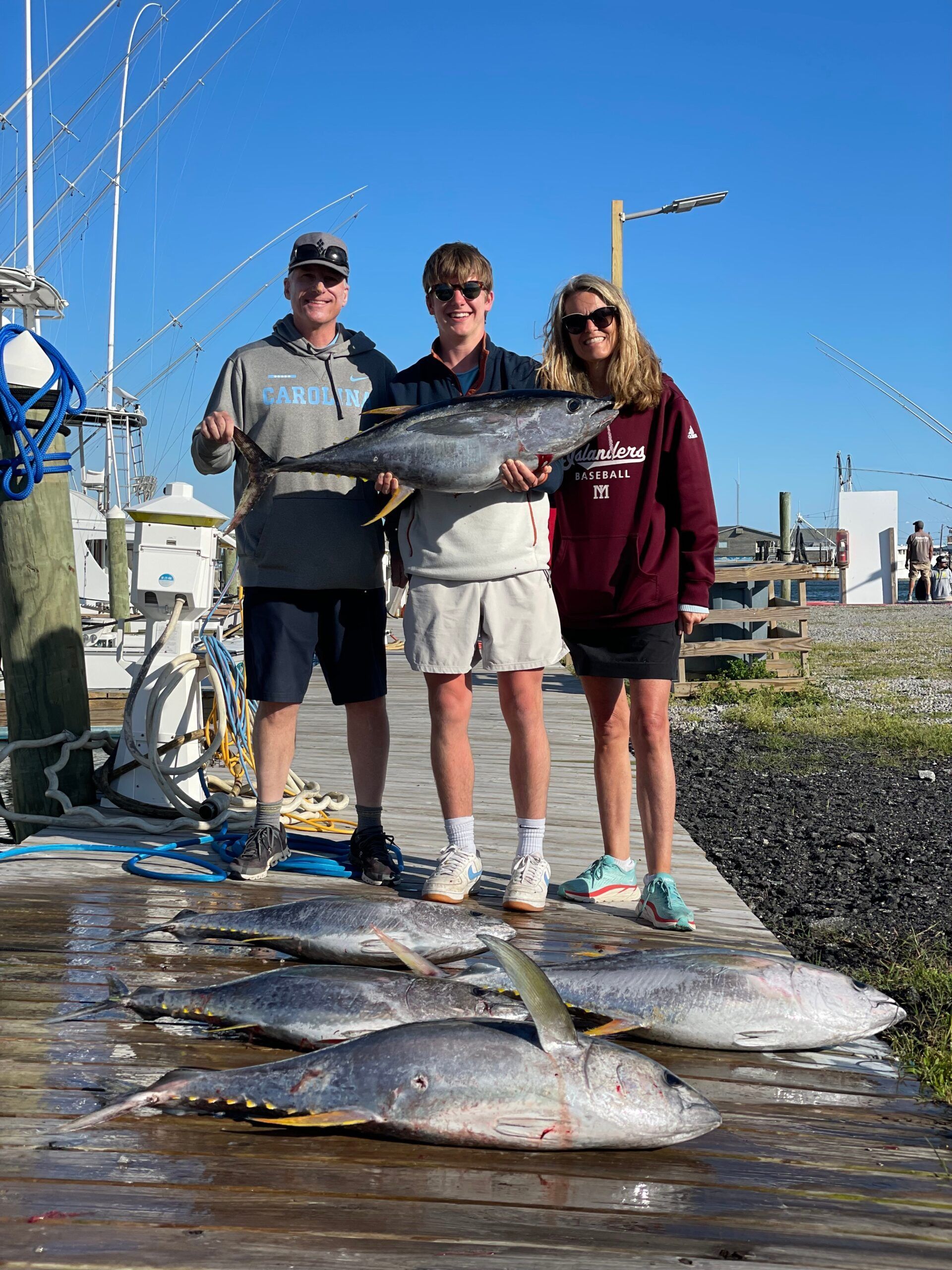A group of people standing on a dock holding fish.
