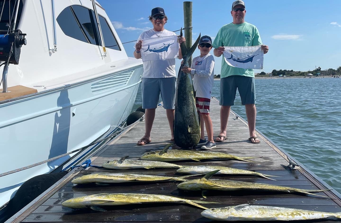 A group of people are standing on a dock holding a large fish.