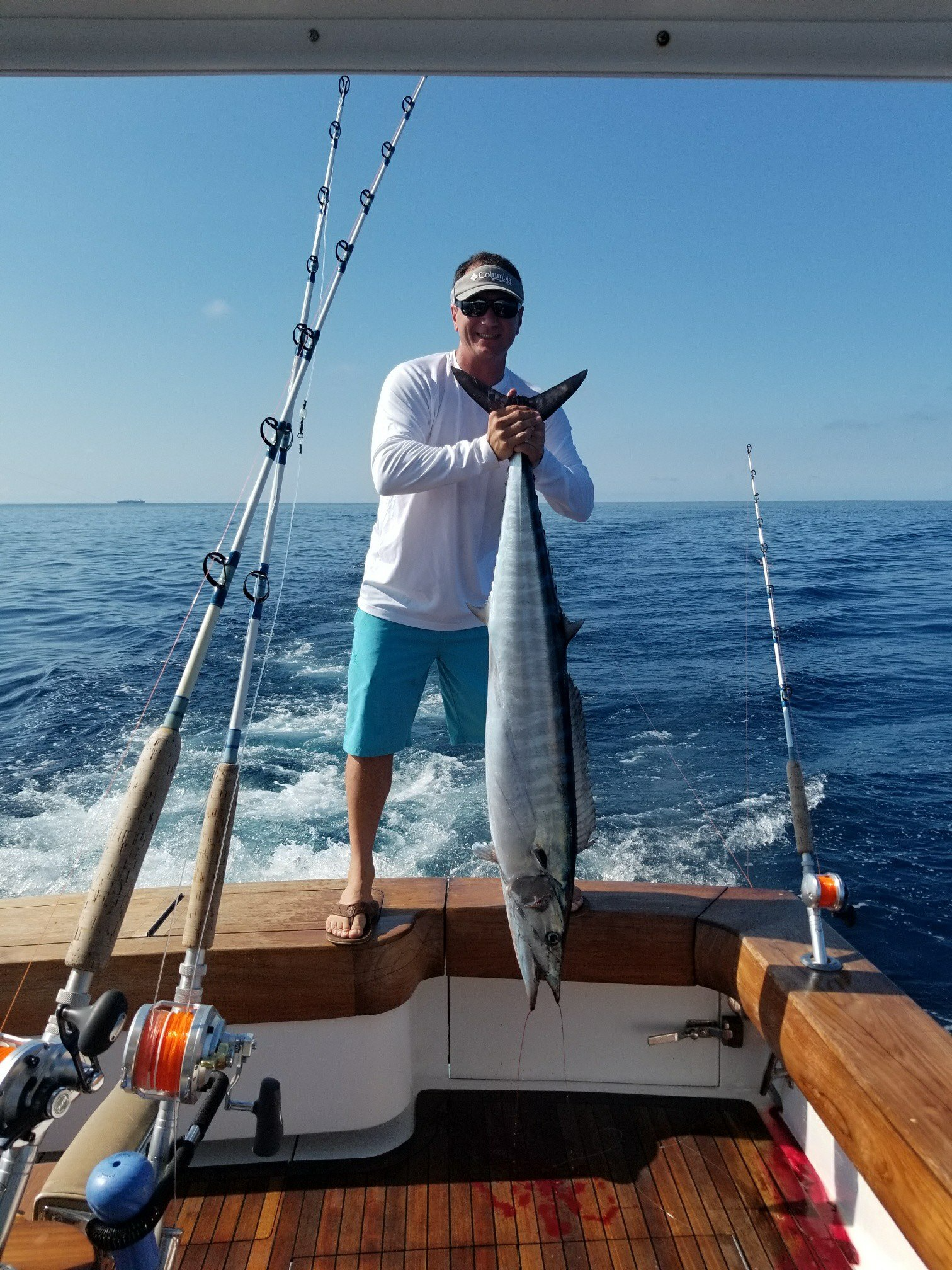 A man is standing on a boat holding a large fish.