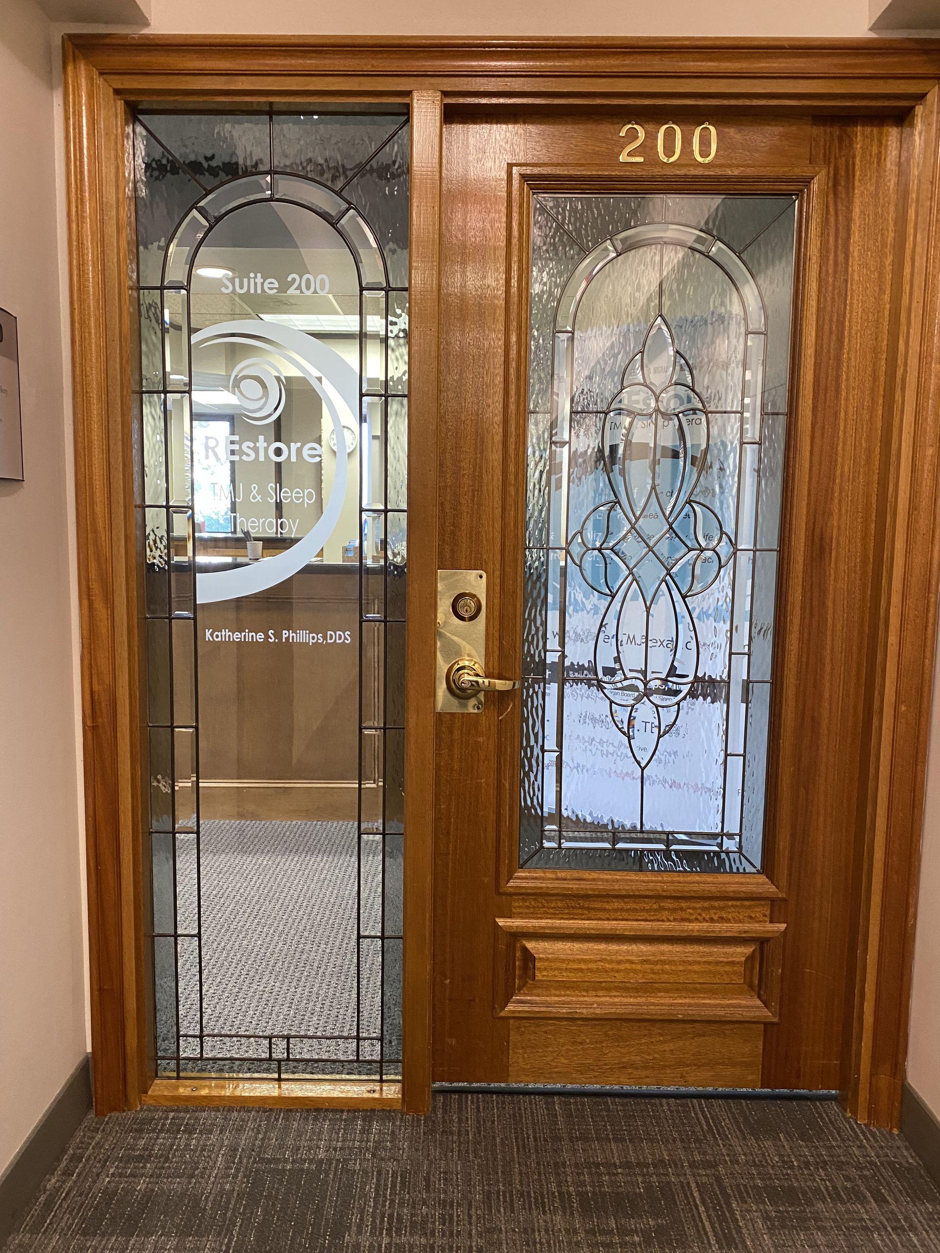 Office door with glass windows peering into the entrance of the Restore TMJ location in Houston, TX.