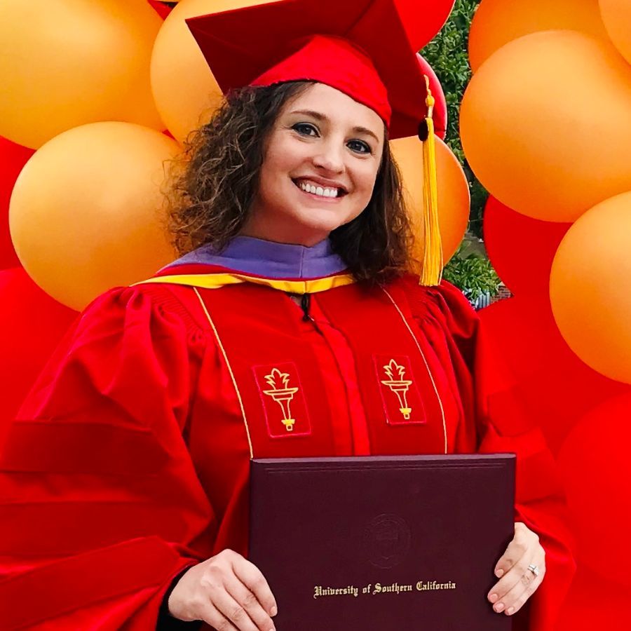 Dr. Katherine Phillips smiling in red graduation robes while earning a Master of Science Degree.