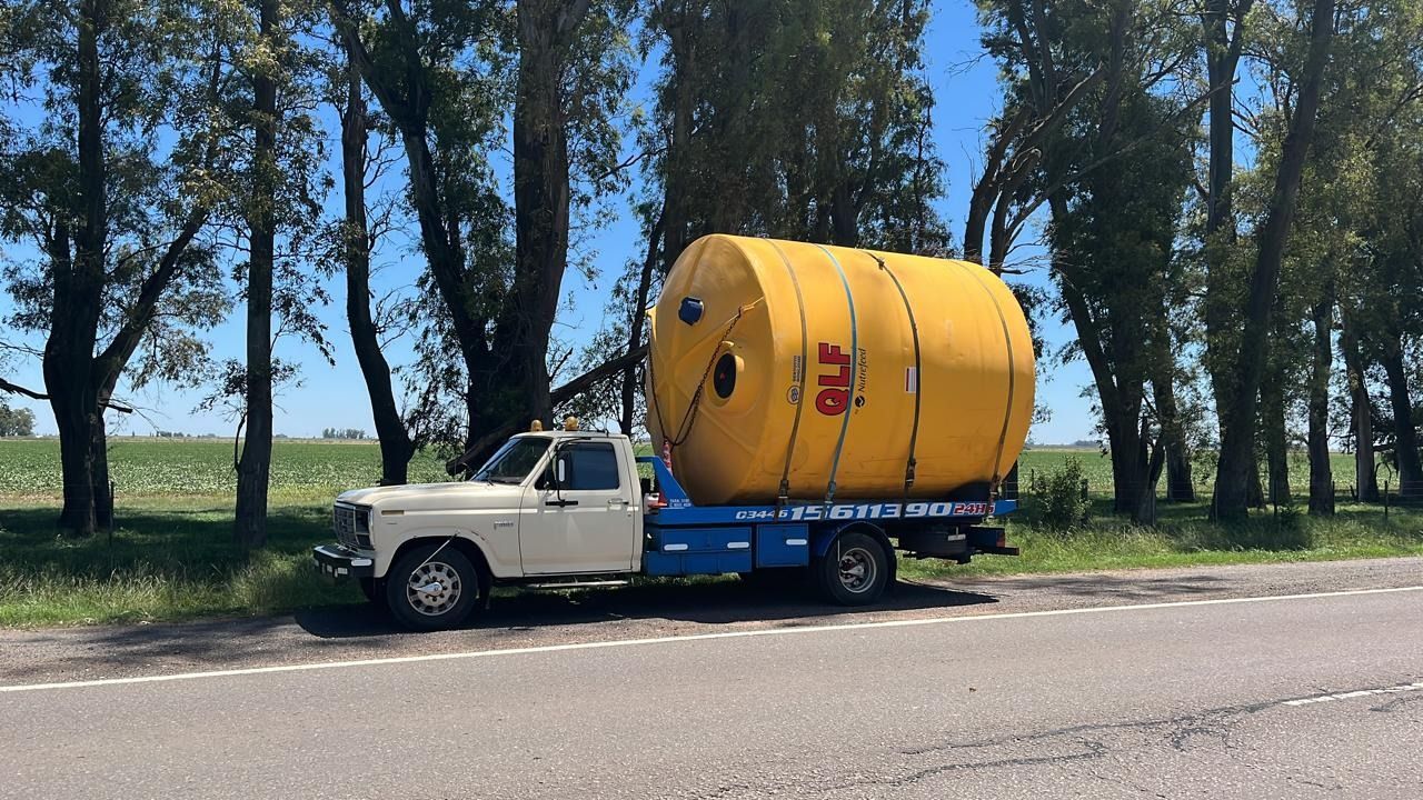 Un camión con un gran tanque amarillo en la parte trasera está estacionado al costado de la carretera.