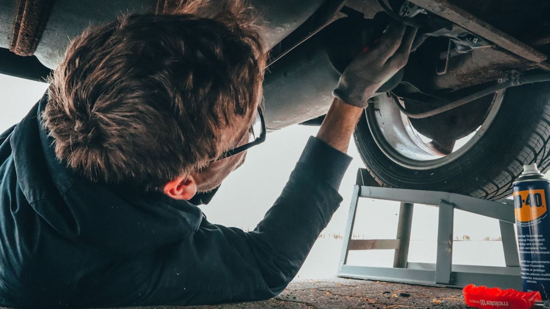 Un hombre está trabajando debajo de un coche en un garaje.