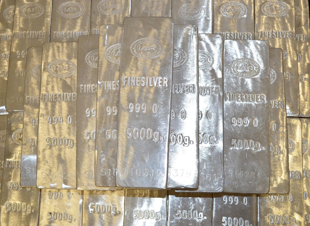 Silver bars stacked, stamped with text indicating purity and weight.