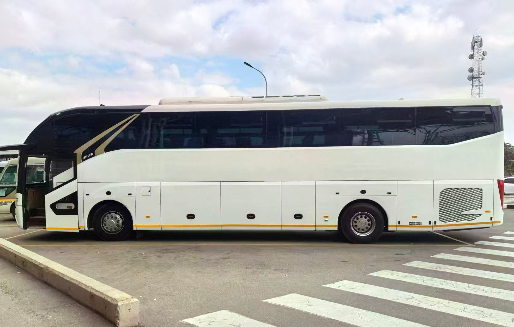 A white tour bus with black window paneling parked on an asphalt lot.