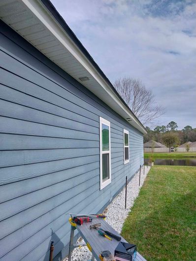 A blue house with a ladder and tools on the side of it.