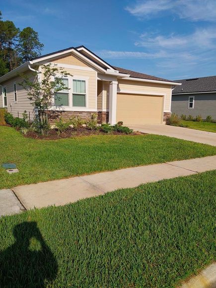 A house with a lot of grass and a sidewalk in front of it.