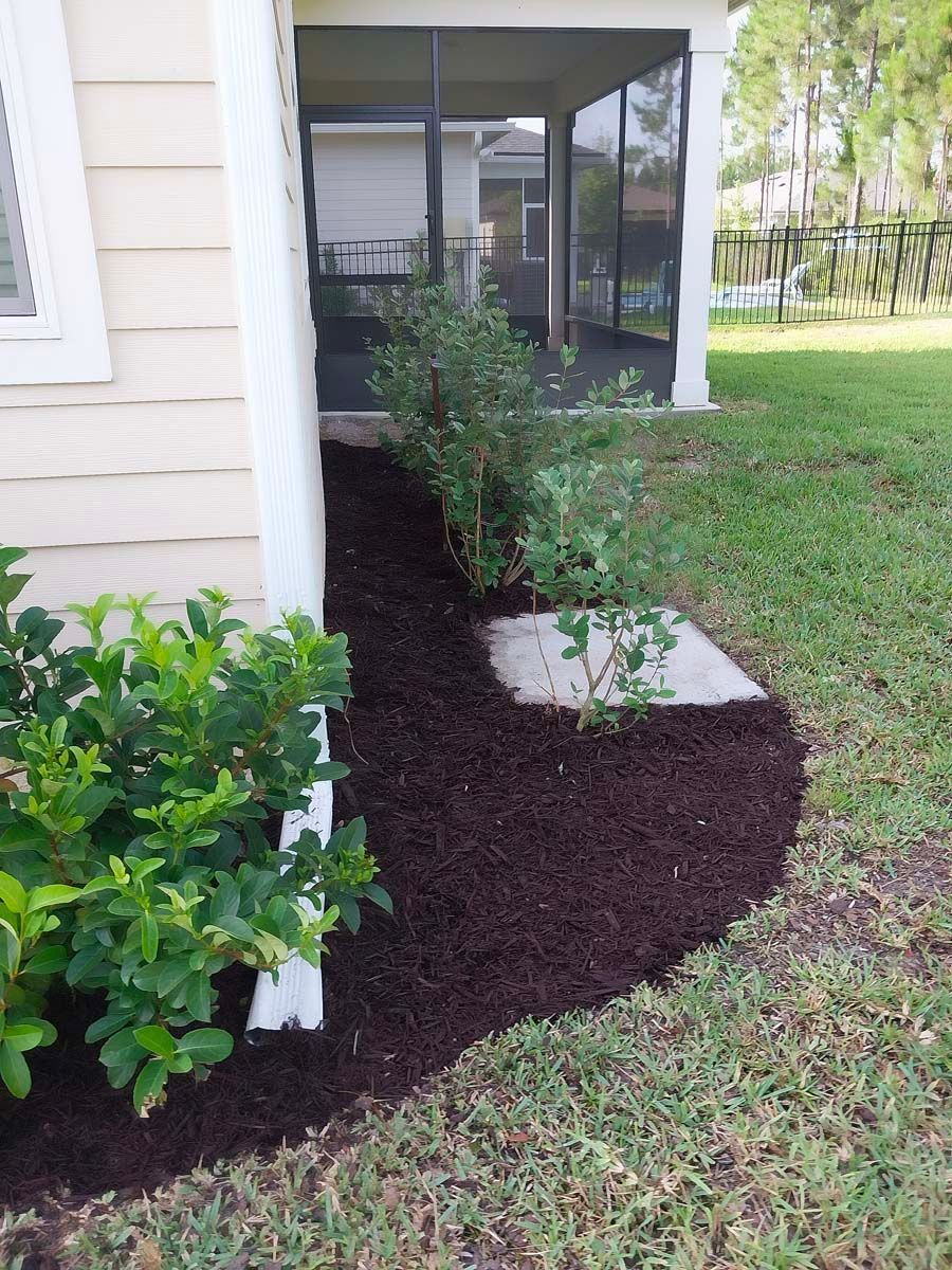 A house with a screened in porch and a lot of mulch on the side of it.