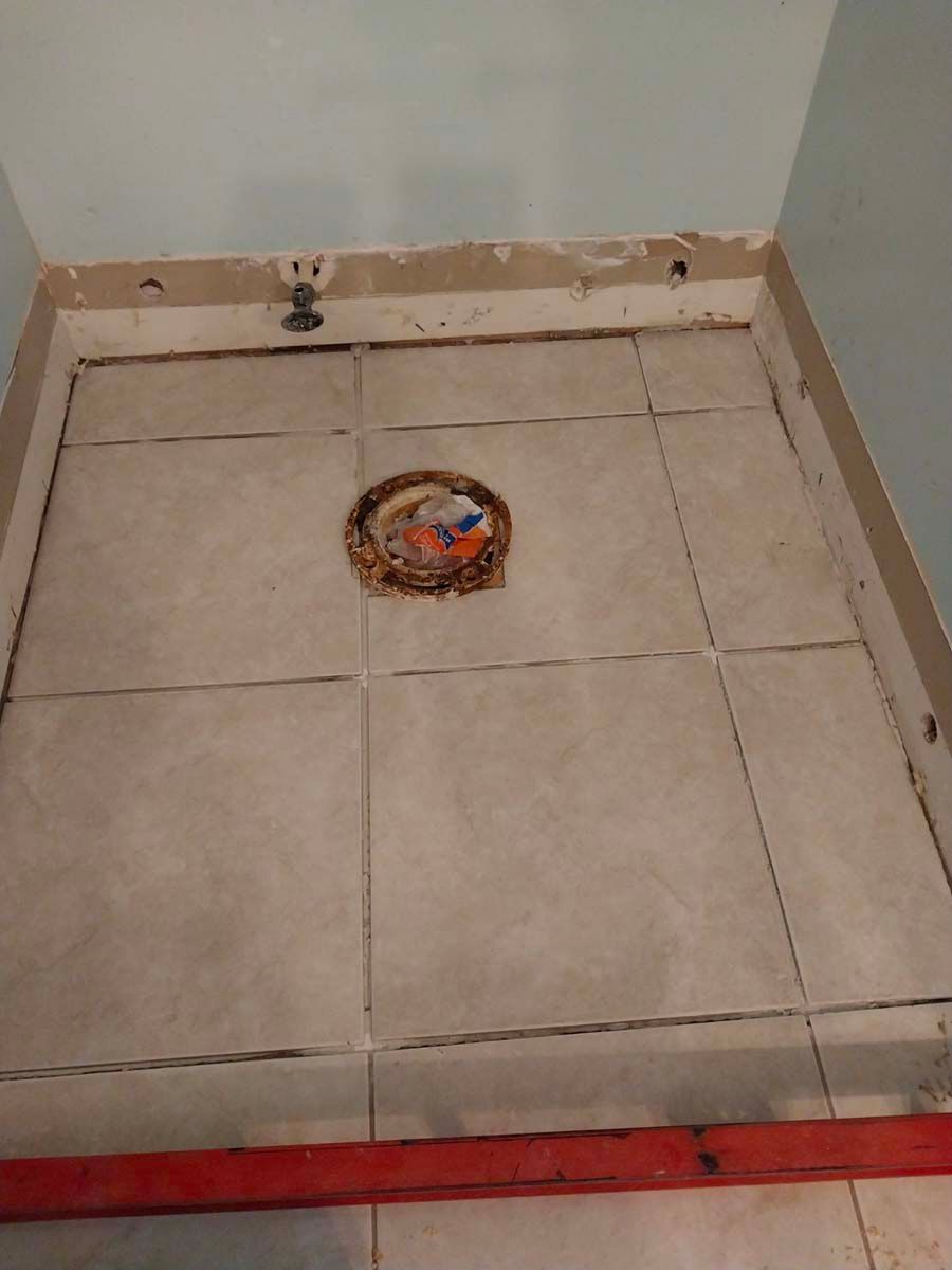 A tiled floor in a bathroom with a toilet drain.