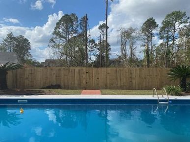 A large swimming pool with a wooden fence surrounding it.