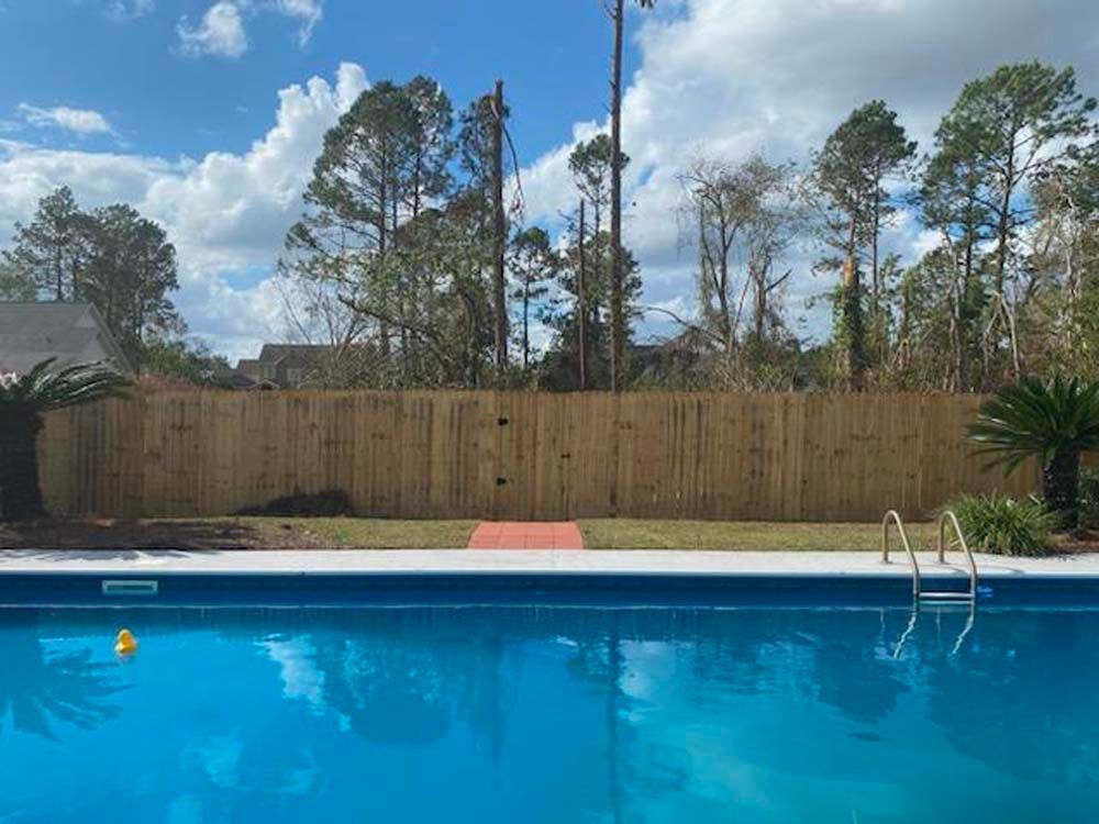 A large swimming pool with a wooden fence surrounding it.