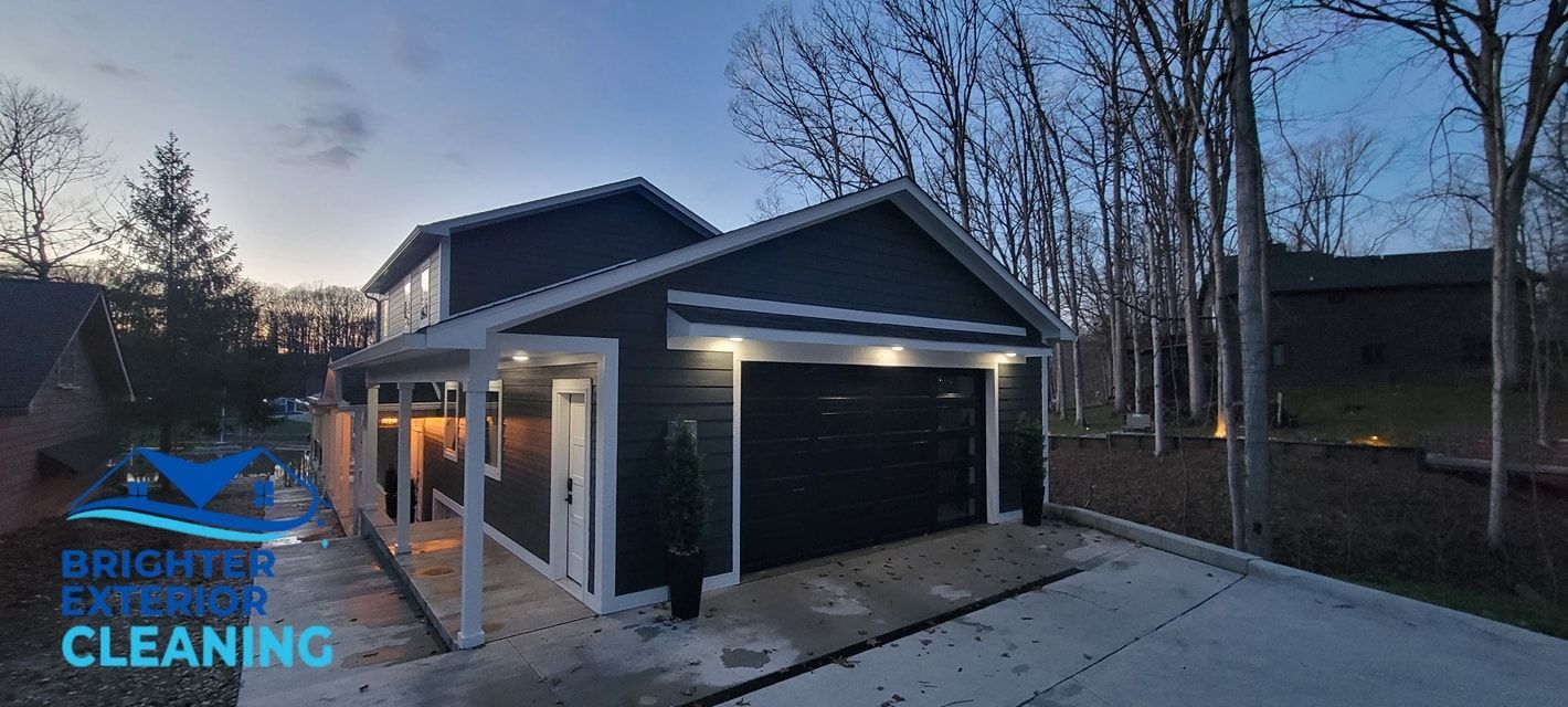 A black garage with a porch and trees in the background.