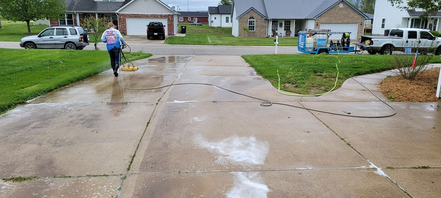 A person is walking down a wet sidewalk in front of a house.