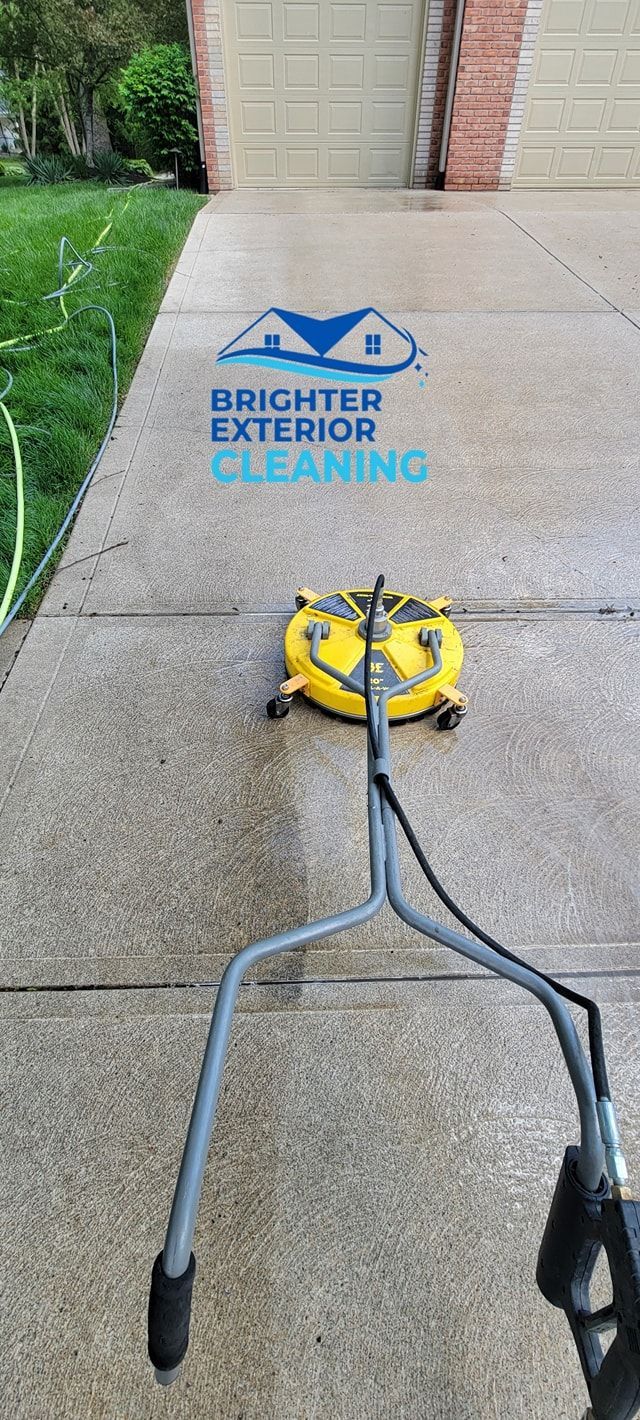 A concrete driveway is being cleaned with a machine.