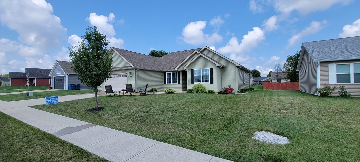 A house with a lush green lawn and a sidewalk in front of it.