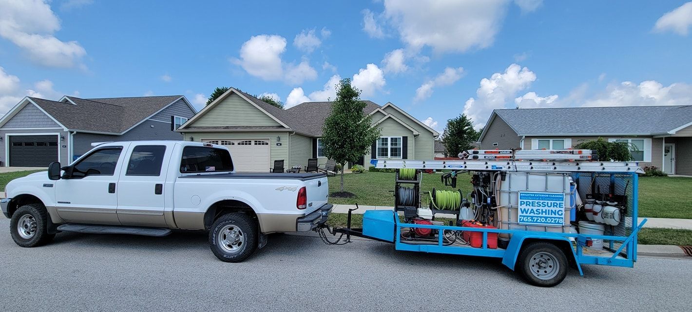 A white truck with a trailer attached to it is parked in front of a house.