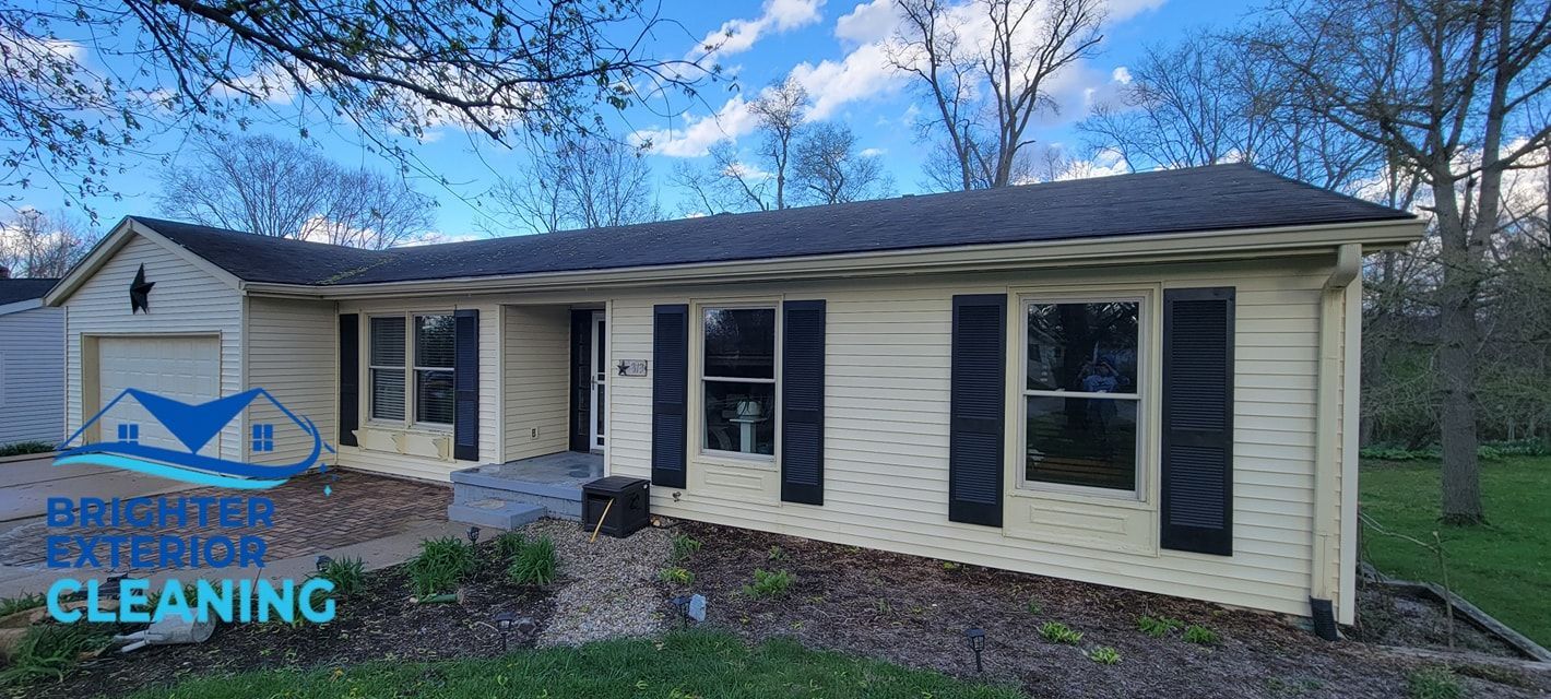 A large white house with black shutters is sitting in the middle of a grassy field.