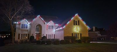 A large house is decorated with christmas lights at night.