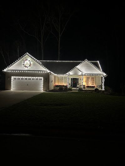 A house with christmas lights on it is lit up at night.