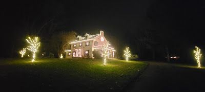A large white house is decorated with christmas lights at night.