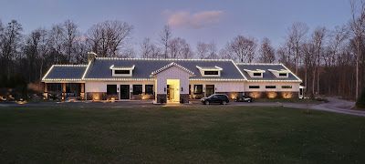 A large house with christmas lights on the roof is lit up at night.
