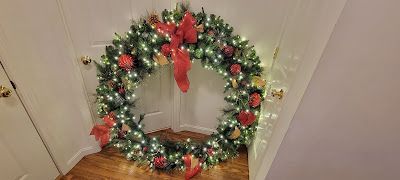 A large christmas wreath is hanging on a door in a hallway.