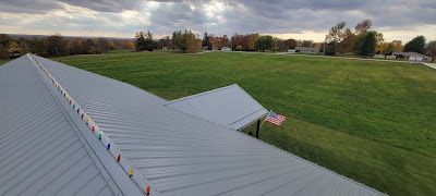 An aerial view of a roof with christmas lights on it and a field in the background.