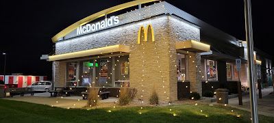 A mcdonald 's restaurant is decorated with christmas lights at night.