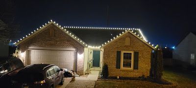 A house with christmas lights on the roof is lit up at night.