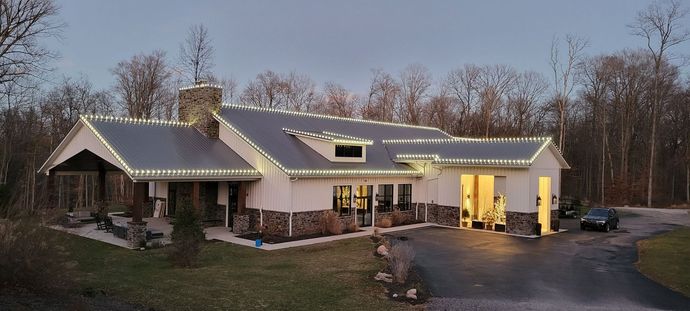 A large white house with christmas lights on the roof.