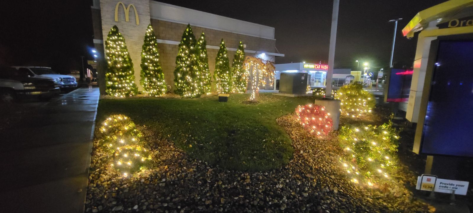 A mcdonald 's restaurant is decorated with christmas lights at night.