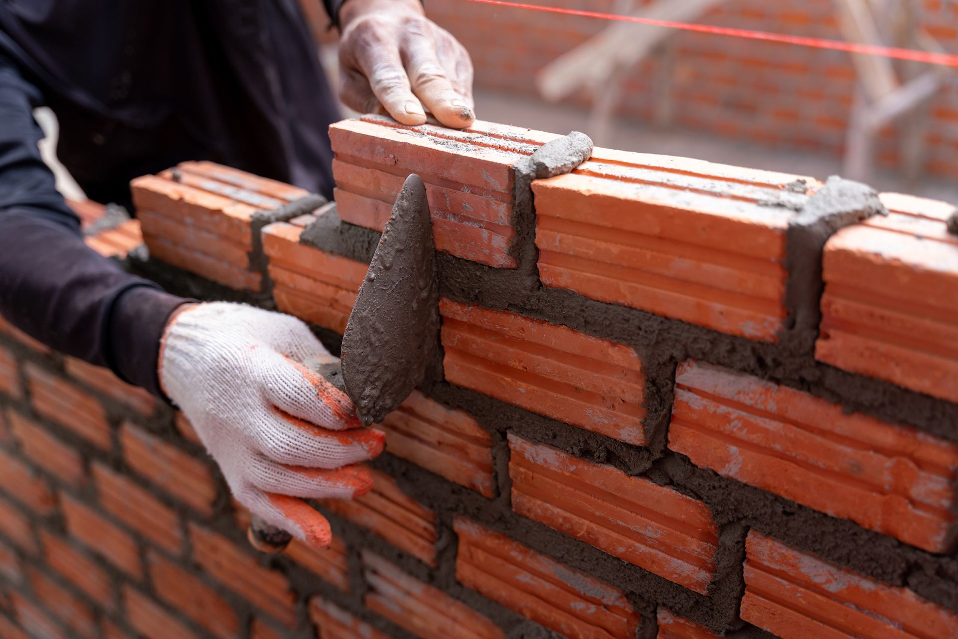 Masonry installation contractor installing bricks on a construction site.