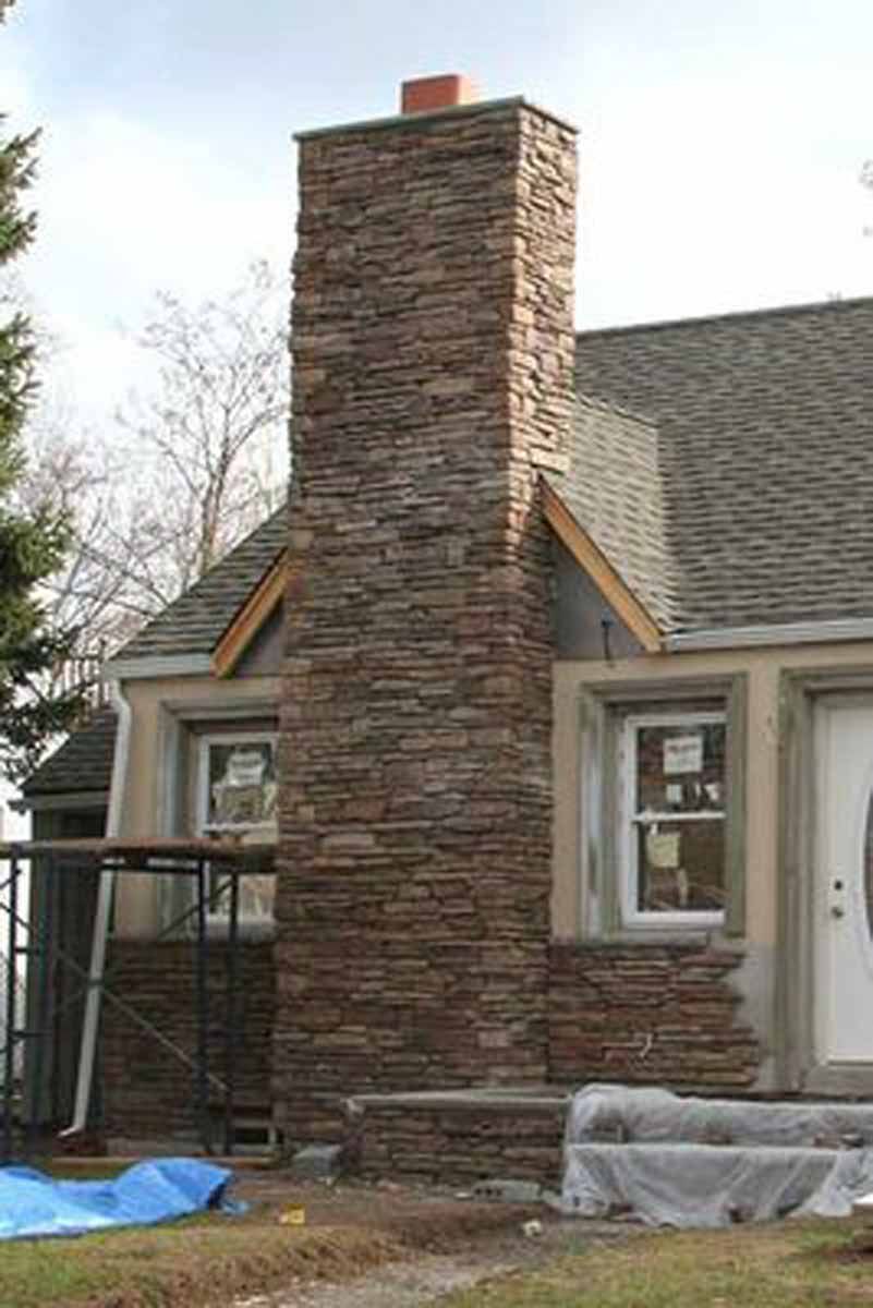 Stone chimney rising from a house, windows with unfinished stone facade.