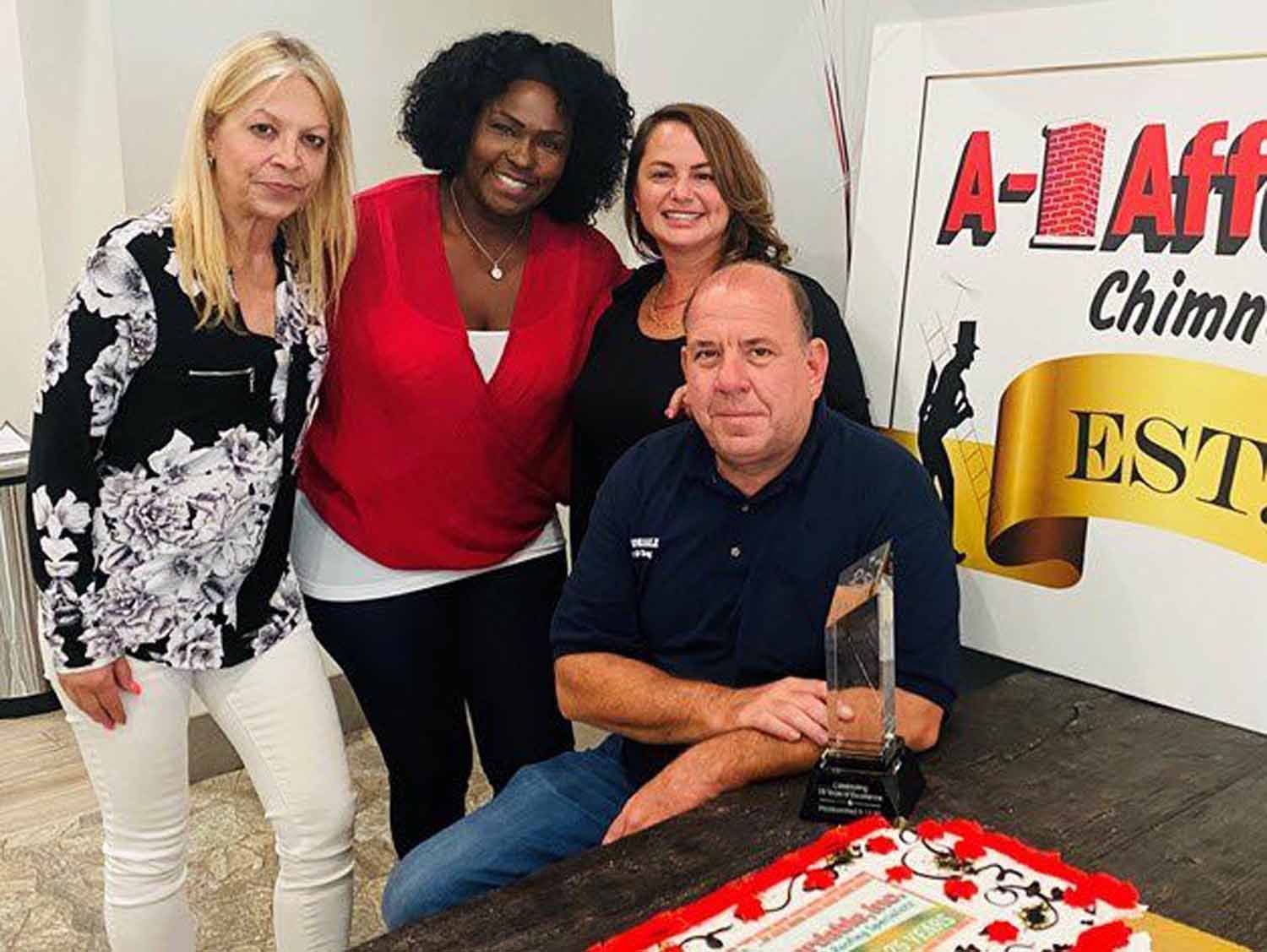 Group celebrates with cake and award near