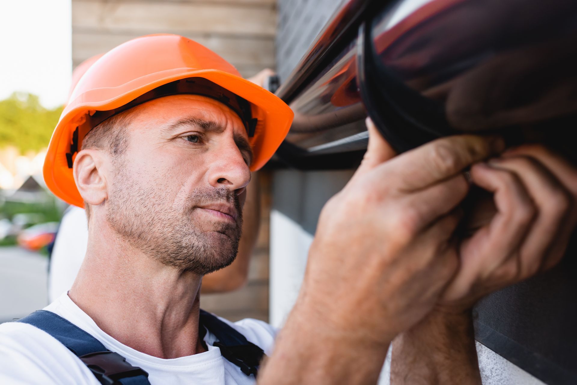 Selective focus of a builder working with a rain gutter on the facade of a building.