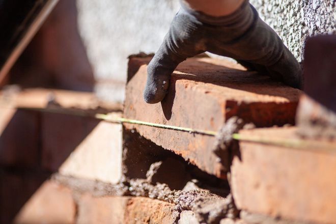 A person is laying bricks on a wall. A person is laying bricks on a wall.