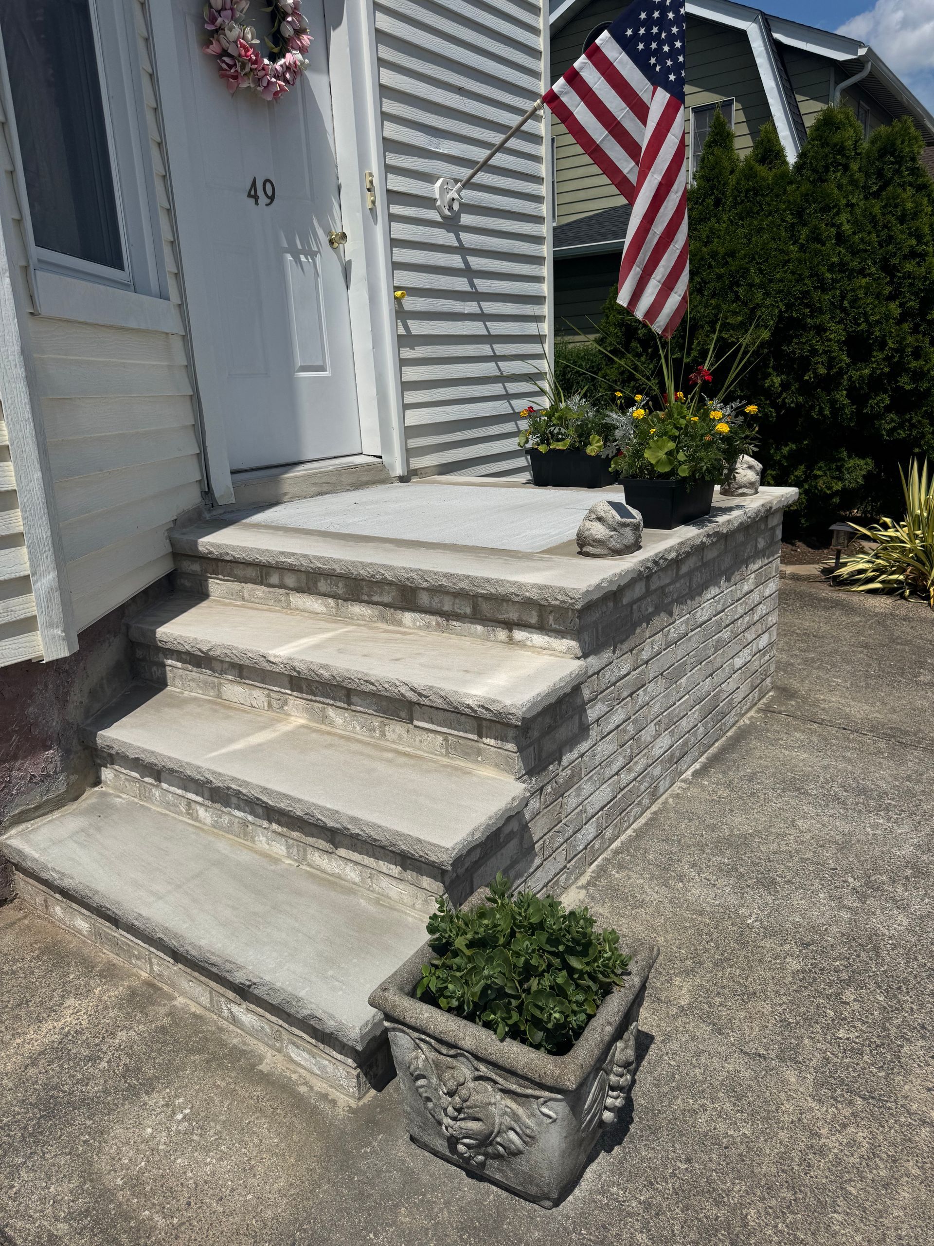 Stone steps lead to a house with an American flag, flower pots. House number 40.