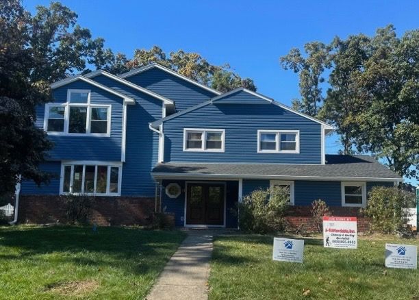 Blue house with white trim and a walkway on a sunny day.