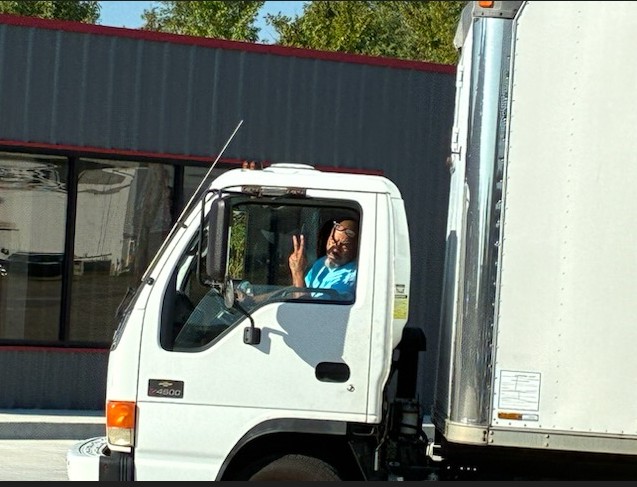 Moving truck parked in front of a brick house on a sunny day.